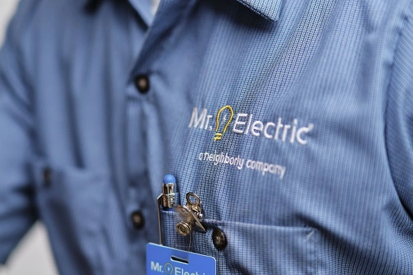 Close Up of a Man's Chest in a Blue Work Shirt with a Mr. Electric Logo Embroidered on it and a Pen in the Pocket