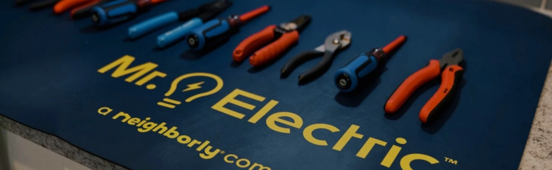 Close Up of a Man’s Chest in a Blue Work Shirt with a Mr. Electric Logo Embroidered on it and a Pen in the Pocket